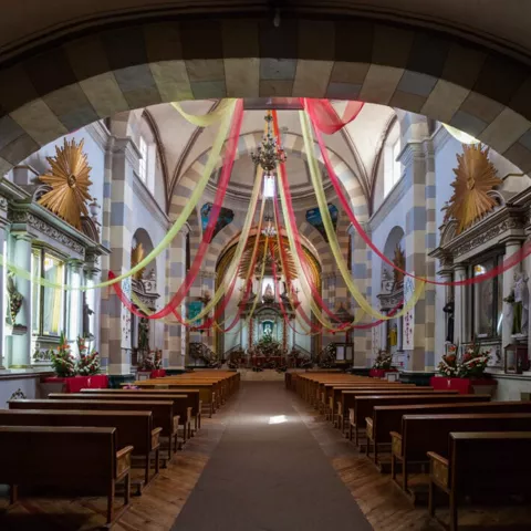 Interior de iglesia con bancos y cintas decorativas colgantes