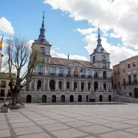 Edificio institucional de piedra con dos torres en gran plaza