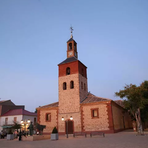 Plaza al atardecer con templo de piedra iluminado.