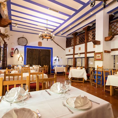 Salón rústico con vigas azules y mesas preparadas