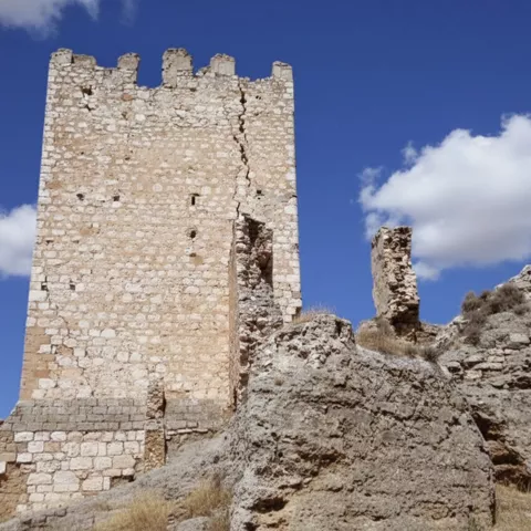 Torre de fortaleza de piedra junto a restos de muralla