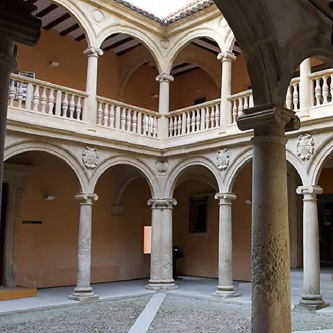 Claustro interior con columnas de piedra, arcos y galerías superiores.