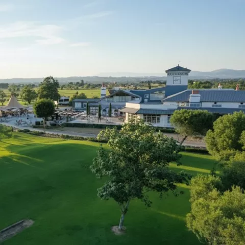 Panorama del campo con césped amplio y edificio principal a lo lejos.
