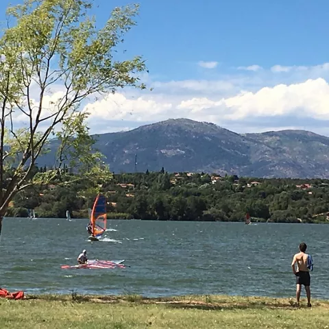 Personas practicando windsurf en un lago rodeado de montañas