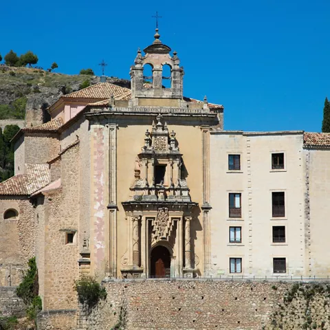 Iglesia y antiguo convento sobre muralla de piedra.