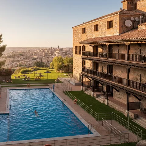 Piscina al aire libre con jardín y vistas a ciudad al atardecer.