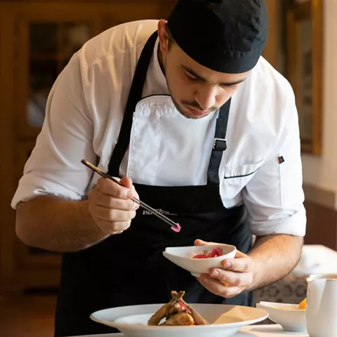 Cocinero decorando plato en sala luminosa