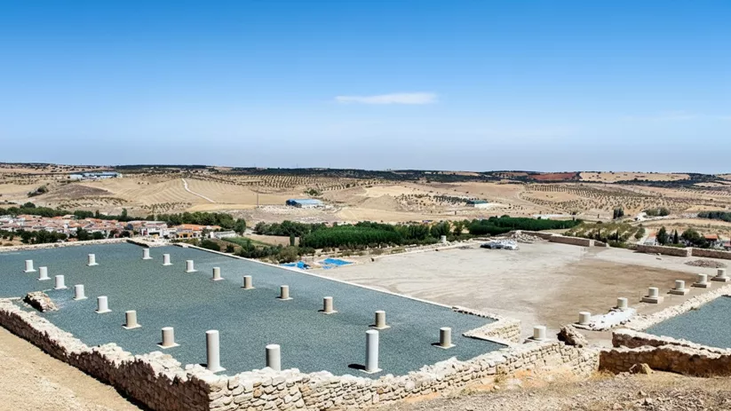 Vista panorámica de un yacimiento con columnas y campos al fondo.