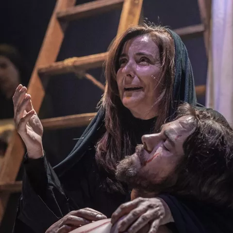 Mujer sostiene a un hombre herido mientras llora en escena