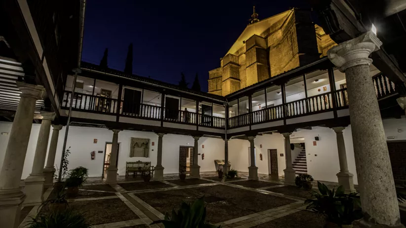 Patio porticado iluminado de noche con arquitectura histórica