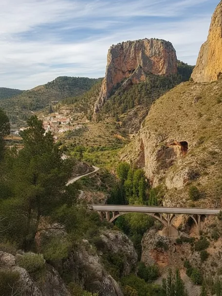 Valle montañoso de Peñascosa con puente de piedra y formaciones rocosas imponentes.