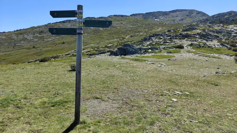 Señal de senderos en pradera de montaña.