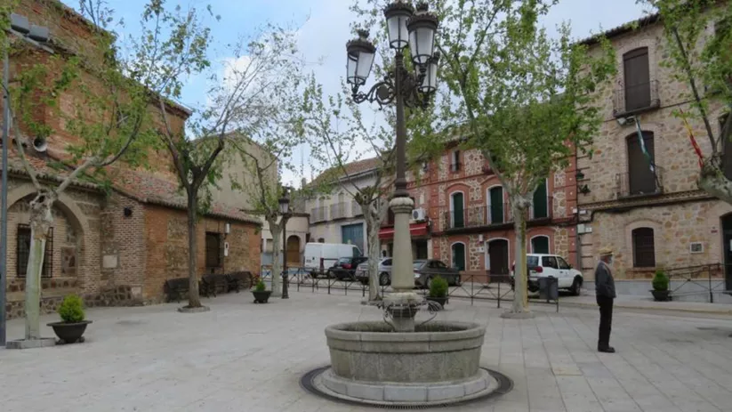 Plaza empedrada con fuente central y edificios tradicionales