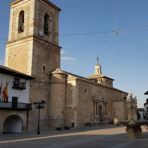Plaza con fuente central y edificios porticados bajo cielo despejado.