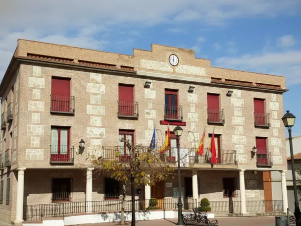Ayuntamiento de ladrillo con reloj y balcones