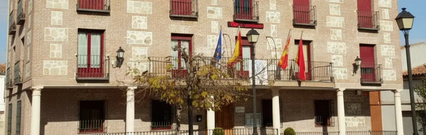 Ayuntamiento de ladrillo con reloj y balcones