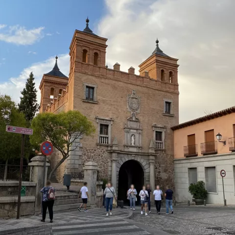 Acceso histórico con arco central y peatones cruzando la calzada.