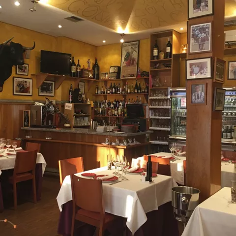 Comedor clásico con barra, mesas vestidas y decoración taurina.