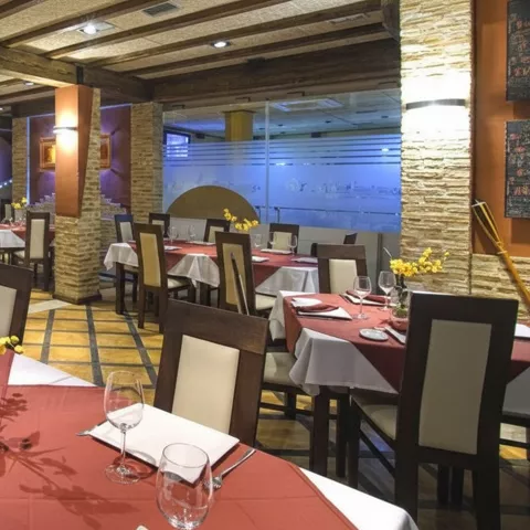 Salón de restaurante con mesas elegantes junto a grandes ventanales.