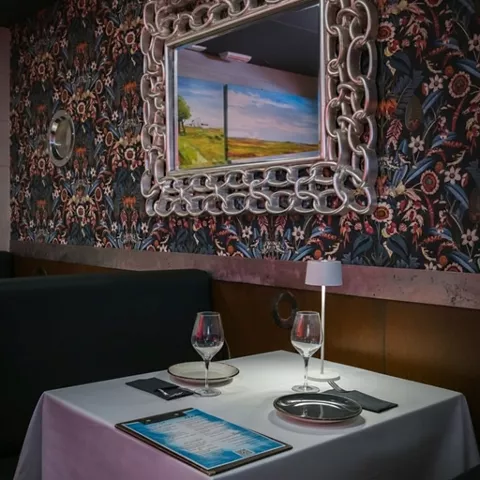 Mesa para dos junto a pared estampada y espejo decorativo.