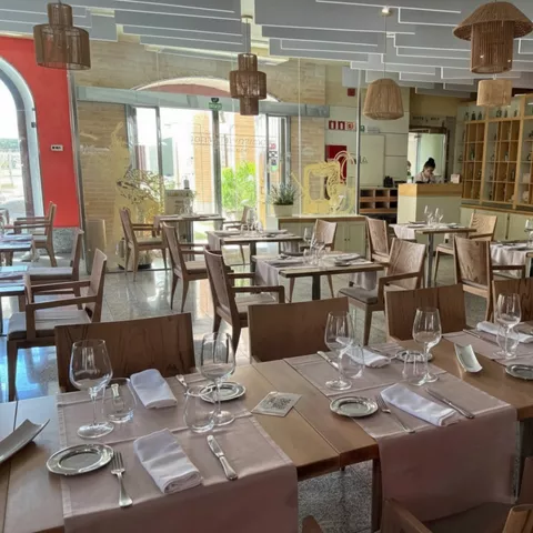 Comedor moderno con mesas de madera y copas de vino preparadas.