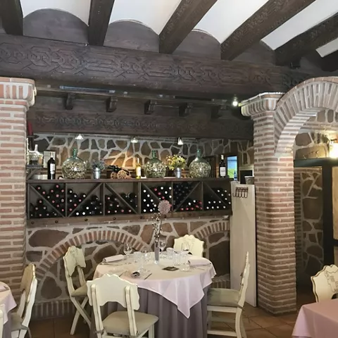 Rincón con mesa redonda junto a botellero empotrado y arcos de ladrillo.