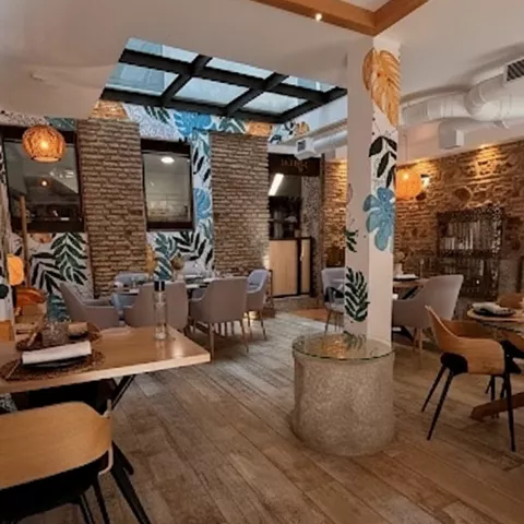 Salón contemporáneo con mesas separadas, techo decorativo y suelo de madera.