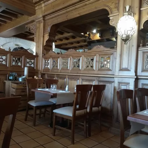 Comedor rústico con paneles de madera tallada y mesas preparadas.