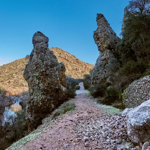 Camino entre rocas y río en desfiladero.