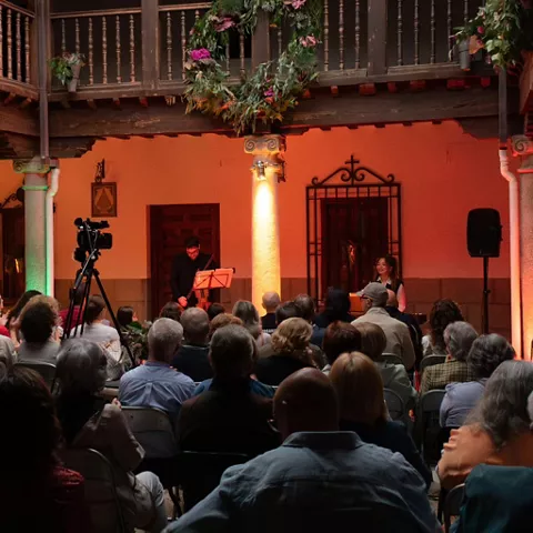 Recital en patio con iluminación cálida y asistentes