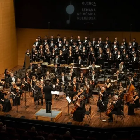Orquesta sinfónica y coro en escenario iluminado