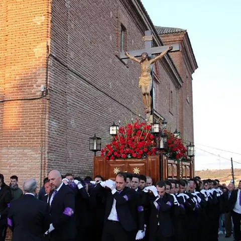 Procesión con imagen de un crucificado portada por un grupo de personas.