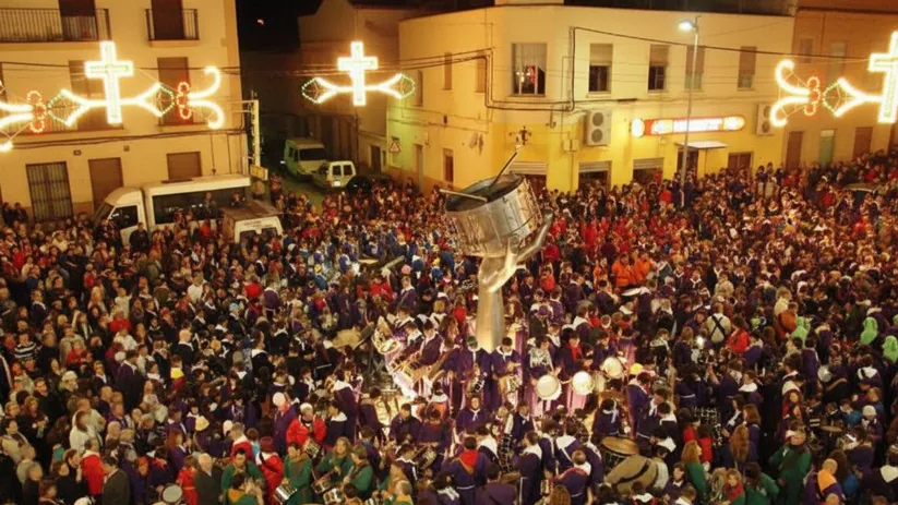 Multitud nocturna rodea monumento con gran tambor mientras suenan percusiones.