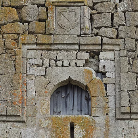 Ventana apuntada con escudo sobre muro de sillería.