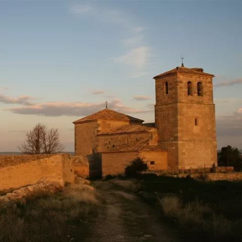 Iglesia al atardecer con muralla y paisaje abierto