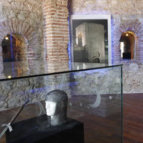 Interior con muros de piedra y vitrina expositiva.
