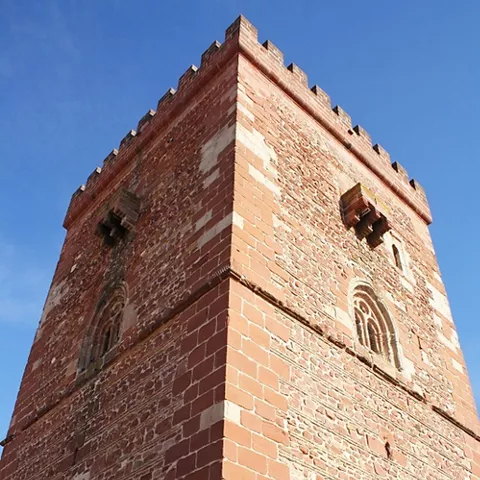 Torre de ladrillo con almenas vista en contrapicado.