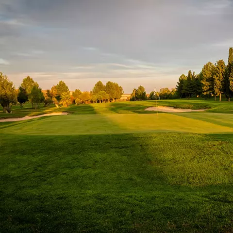 Green con bandera y bunkers al atardecer