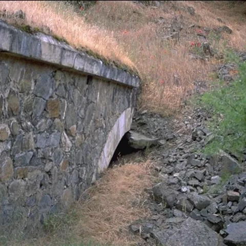Pequeño túnel de piedra junto a arroyo seco
