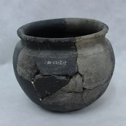 Vasija de cerámica oscura reconstruida a partir de fragmentos.