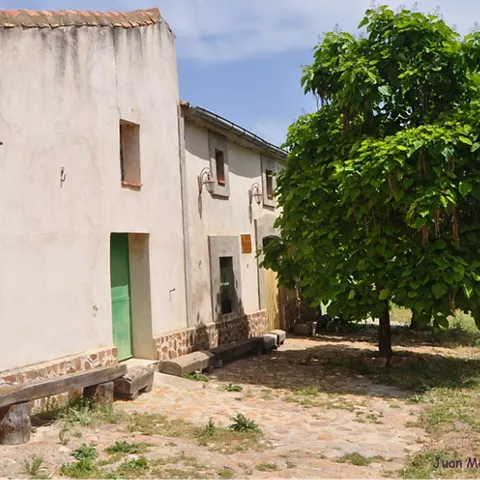 Vista lateral de edificio rural con árbol y bancos