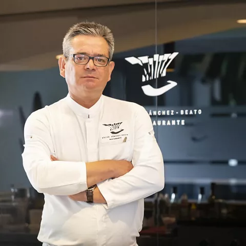 Cocinero posa con los brazos cruzados ante una cristalera del restaurante