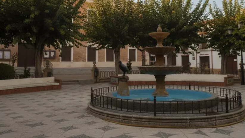 Una plaza de pueblo adoquinada con una fuente ornamental de varios niveles