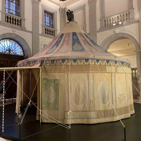 Tienda ceremonial decorada con tejidos ornamentales en el interior de un edificio histórico.