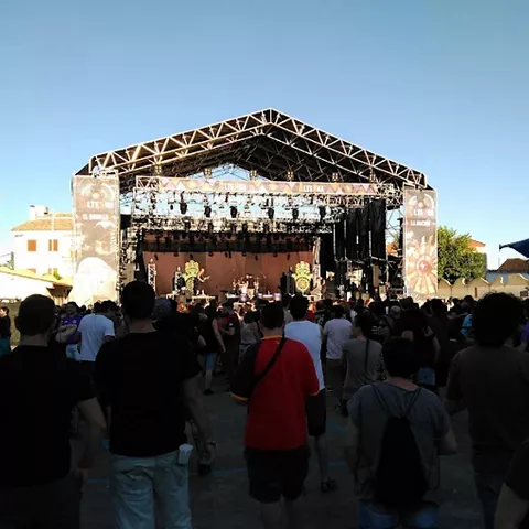 Escenario al aire libre con asistentes frente a la actuación.