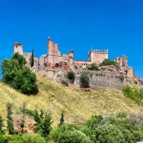 Vista panorámica de castillo en lo alto de una colina bajo cielo azul
