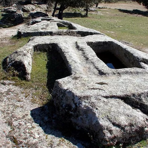 Estructura excavada en roca con cavidades rectangulares en entorno natural.