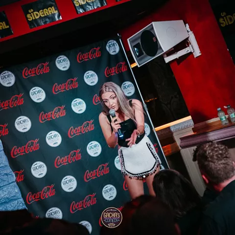 Monologuista actuando con micrófono ante público en sala cerrada.