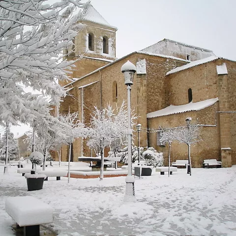 Iglesia de piedra cubierta de nieve en una plaza invernal