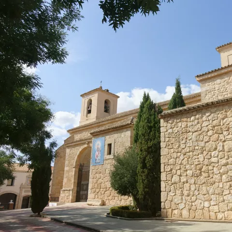 Iglesia de piedra con campanario y árboles junto a la entrada
